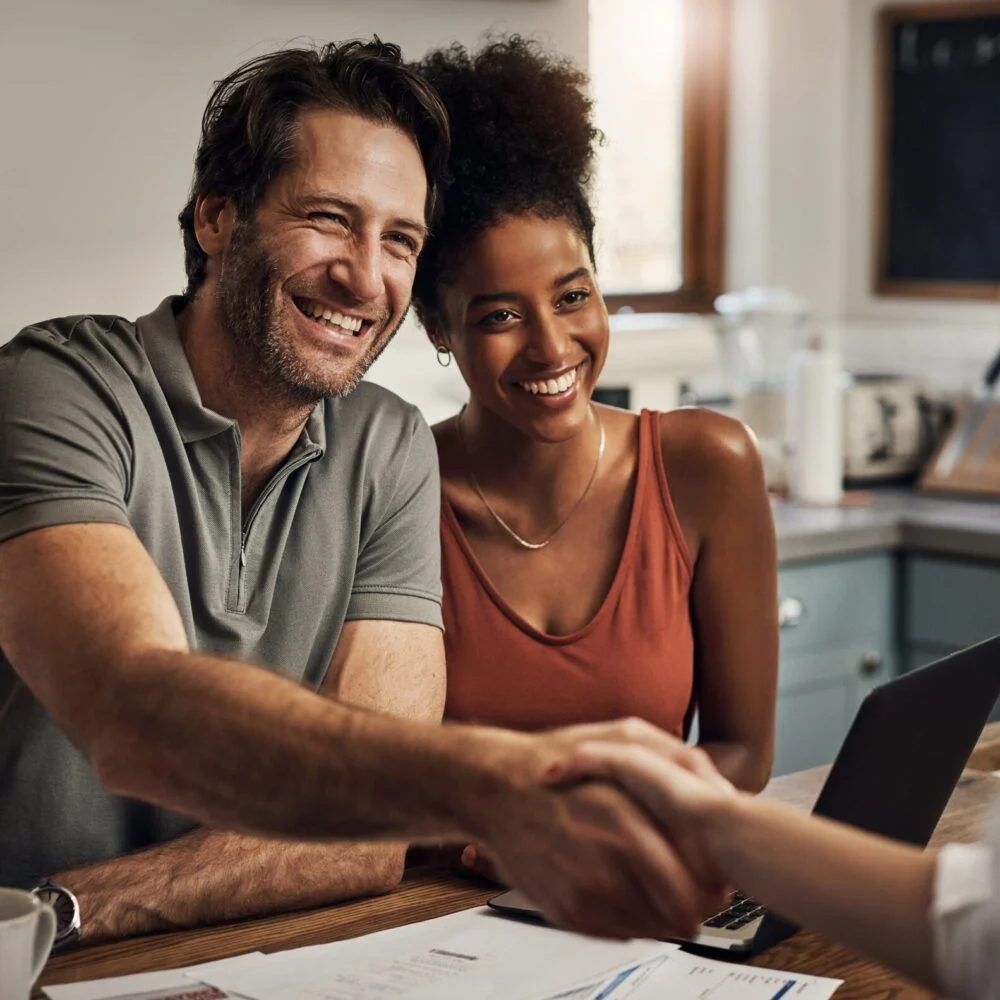 Smiling friends shaking hands across a table